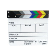 A standard film clapperboard with a white writing surface, black clapper ends, and a row of colored stripes in gray, white, green, red, and yellow. The board is photographed on a plain white background.